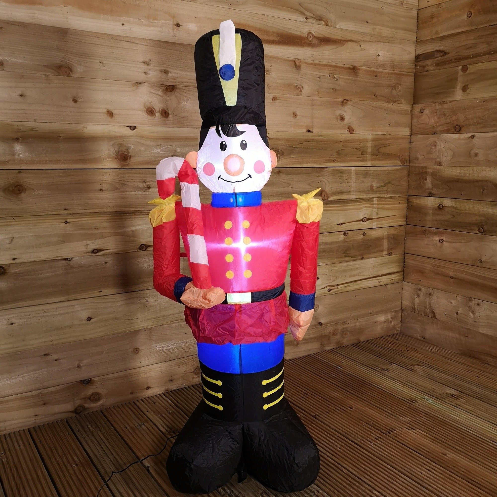 1.2M tall inflatable toy soldier in red and blue uniform, holding a candy cane, with a black hat and cheerful facial features, made of durable material, ideal for Christmas decorations.