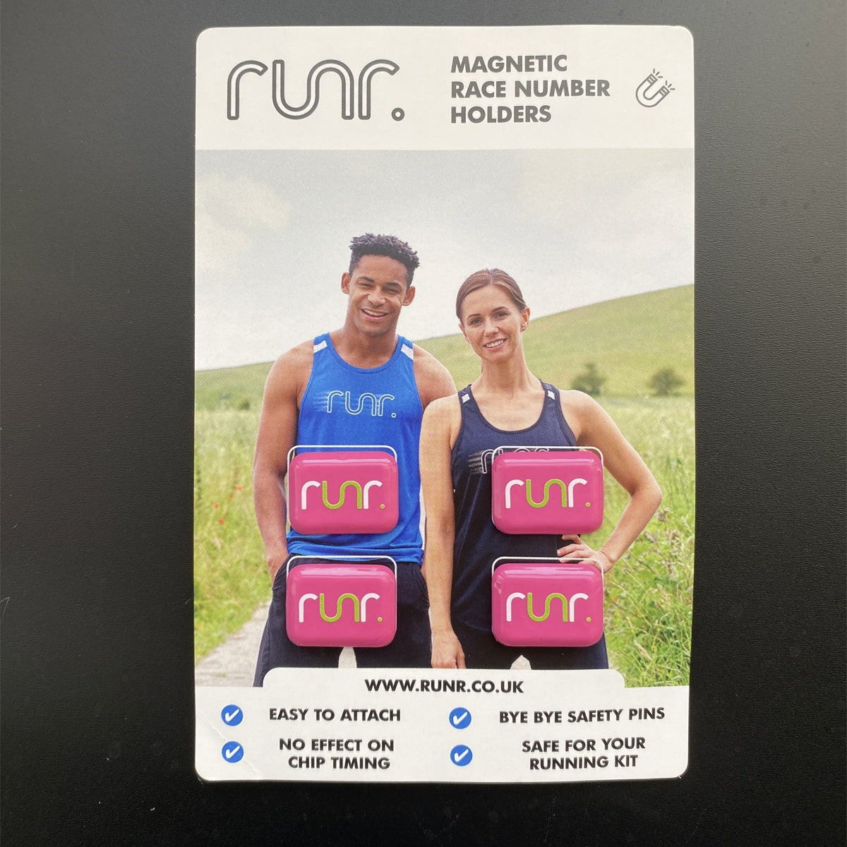 Pink magnetic race number holders with "RUNR" logo, displayed on a card featuring two runners, highlighting easy attachment and no effect on chip timing.