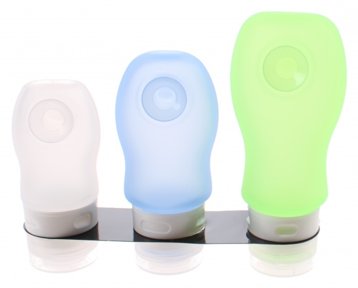 Three silicone travel containers in varying sizes: a clear white, a light blue, and a bright green, all with a round dispensing opening and mounted on a black holder.
