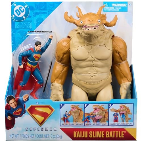 Superman action figure in red and blue costume stands next to a large beige Kaiju monster with a grotesque face, set in a colorful packaging featuring comic-style graphics.