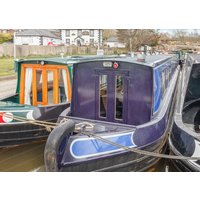 Blue and black narrowboat "Aquarius" with wooden cabin windows, moored alongside other boats on a canal.