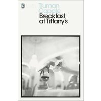 "White paperback book 'Breakfast at Tiffany's' by Truman Capote, featuring a blurred black-and-white cover image."
