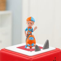 Blippi figurine with orange hat, blue shirt, and suspenders, standing on a red Toniebox base with gray ears.