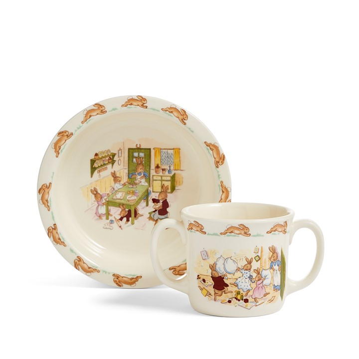 Ceramic baby bowl and two-handle mug set featuring charming Bunnykins illustrations, soft cream color with playful bunny designs around the edges.