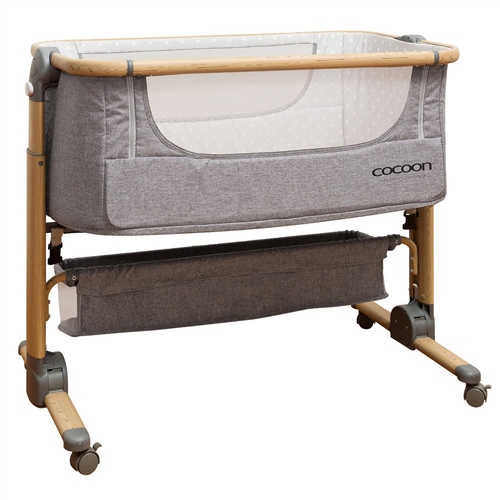 Gray fabric bassinet with a wooden frame, mesh sides, and a lower storage compartment, featuring a modern design and adjustable height for easy access.