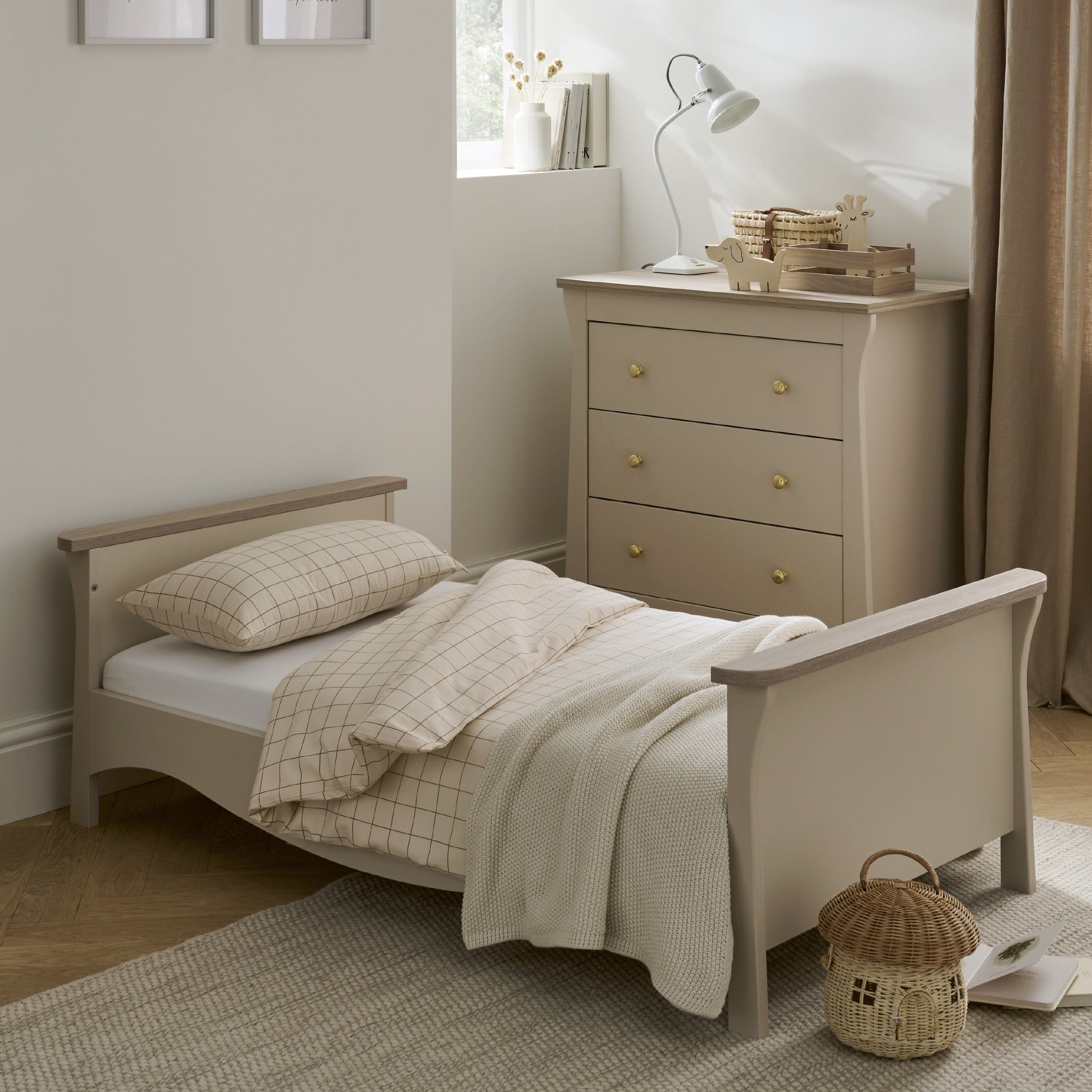 Clara Toddler Bed in cashmere and ash features a smooth, neutral finish, curved edges, and is paired with soft, checkered bedding, set in a cozy, light-filled room.