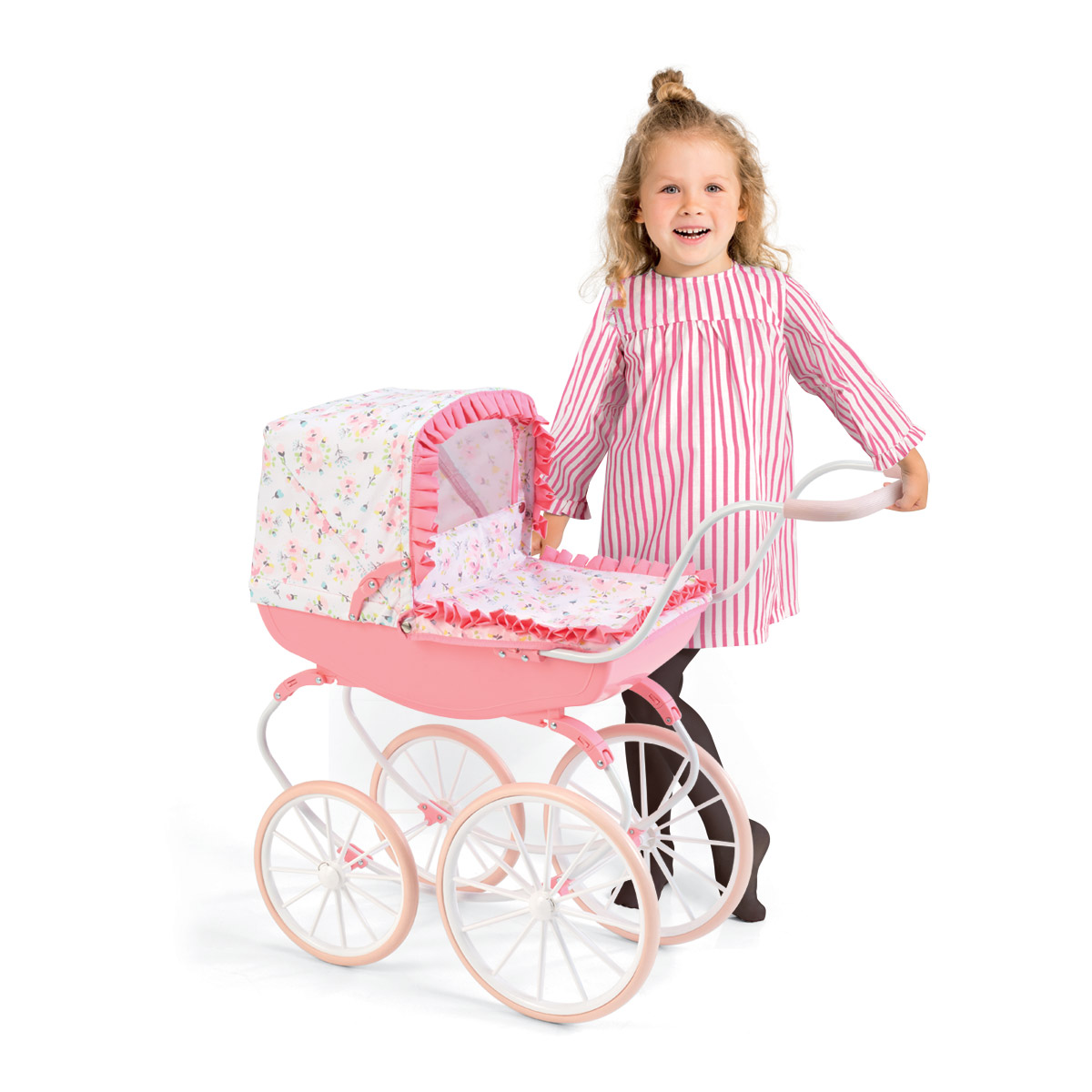 A young girl in a striped dress smiles while pushing a pink vintage-style doll stroller with floral fabric and white wheels.