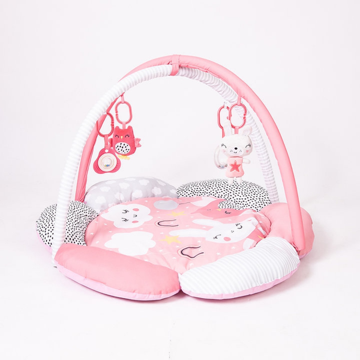 Colorful playgym featuring a soft, padded floral mat in pink and gray with plush toys, including a bunny and owl, hanging from a white arch.