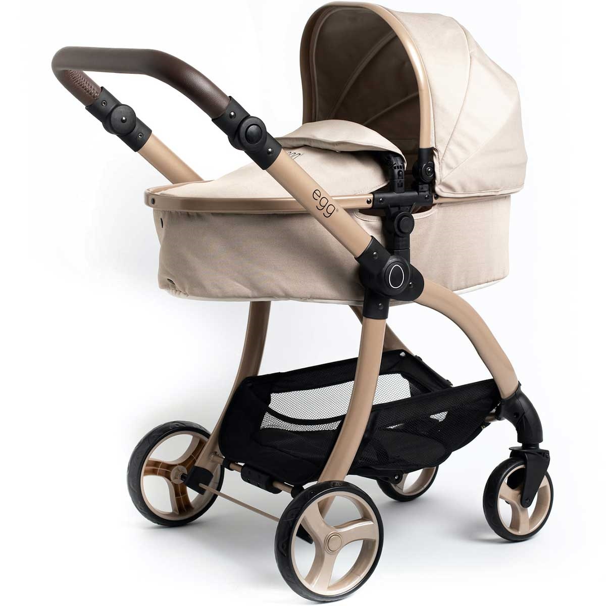 Beige fabric pram with a sleek design, featuring a brown handle, a spacious canopy, and a black mesh storage basket underneath.