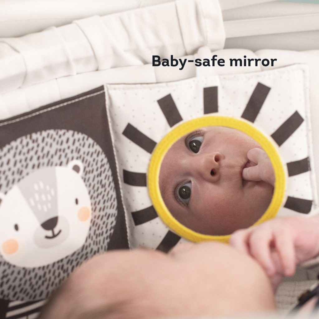 Black and white fabric book featuring a baby-safe mirror surrounded by a yellow sun design, with a bear illustration on one side and a soft, textured finish.