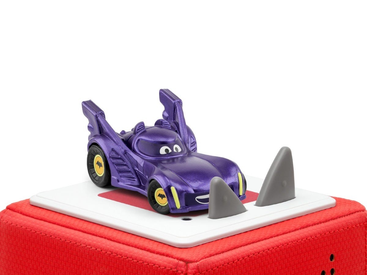 Purple toy car with a smiling face, featuring pointed gray fins and yellow wheels, placed on a red base with a white audio platform.