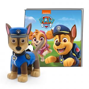 Chase, a brown and tan dog figure, wears a blue police uniform with a badge, standing next to a colorful Paw Patrol book featuring characters in a vibrant landscape.
