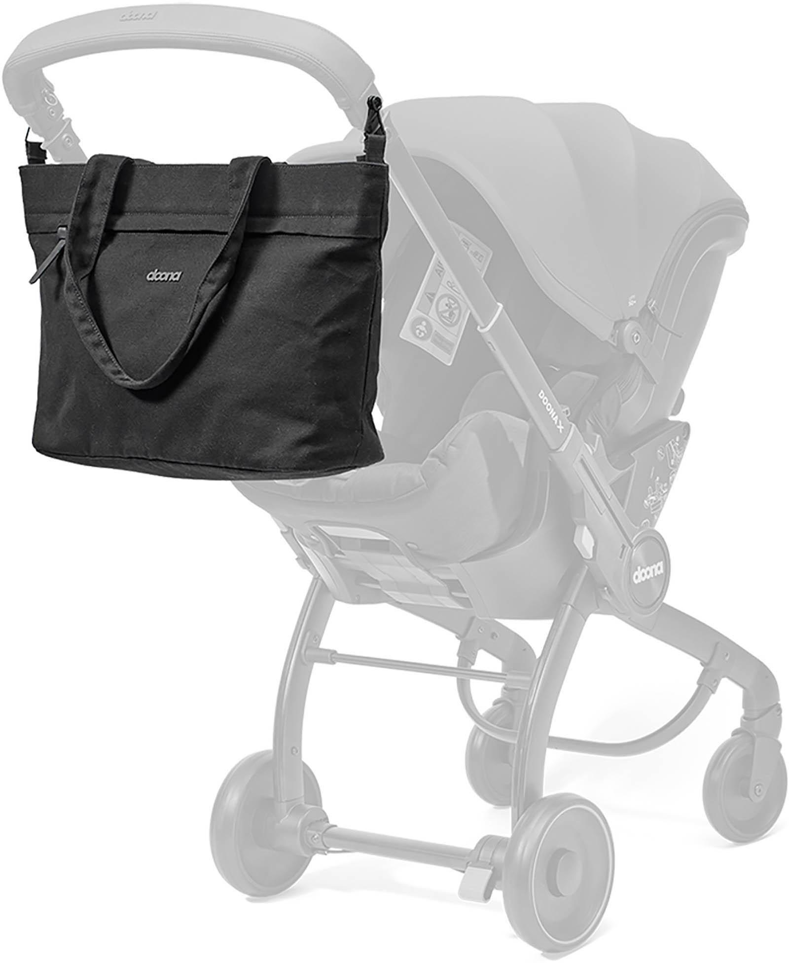 Black Doona tote bag with shoulder straps and zippered pocket, shown attached to a stroller handle.
