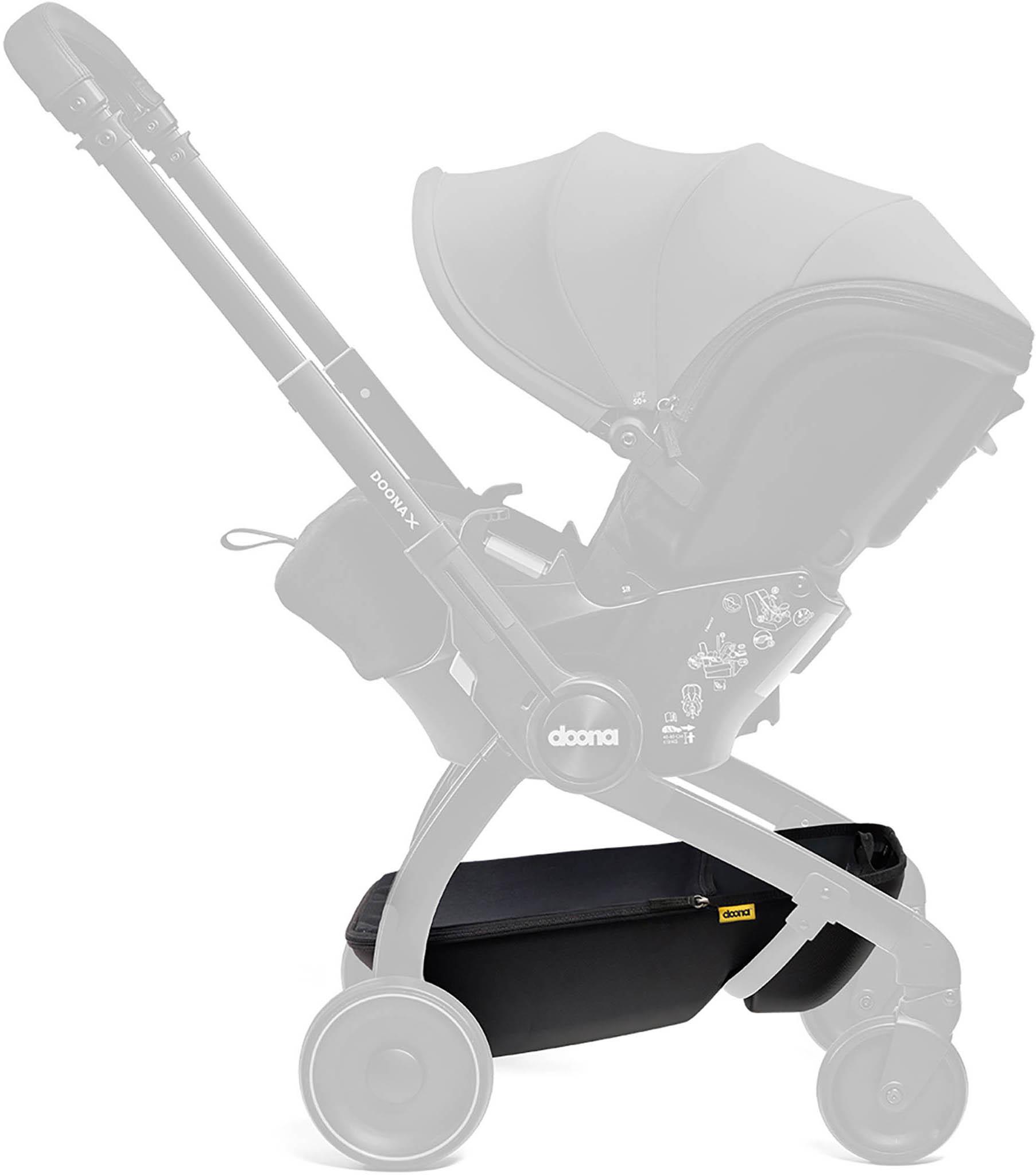 Black Doona X Storage Basket attached to stroller frame, featuring a sleek design with a yellow Doona logo tag.
