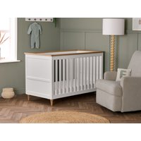 White Obaby Orla cot bed with natural wood top, slatted sides, and solid base, set in a cozy nursery room.