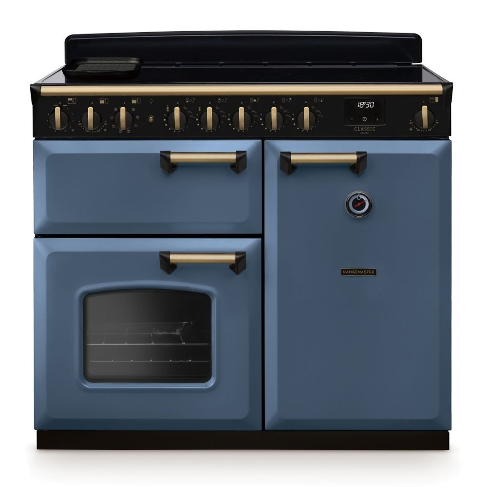 Classic Deluxe 100cm induction range cooker in stone blue with antique brass accents, featuring five control knobs, a glass oven door, and a sleek black induction hob.