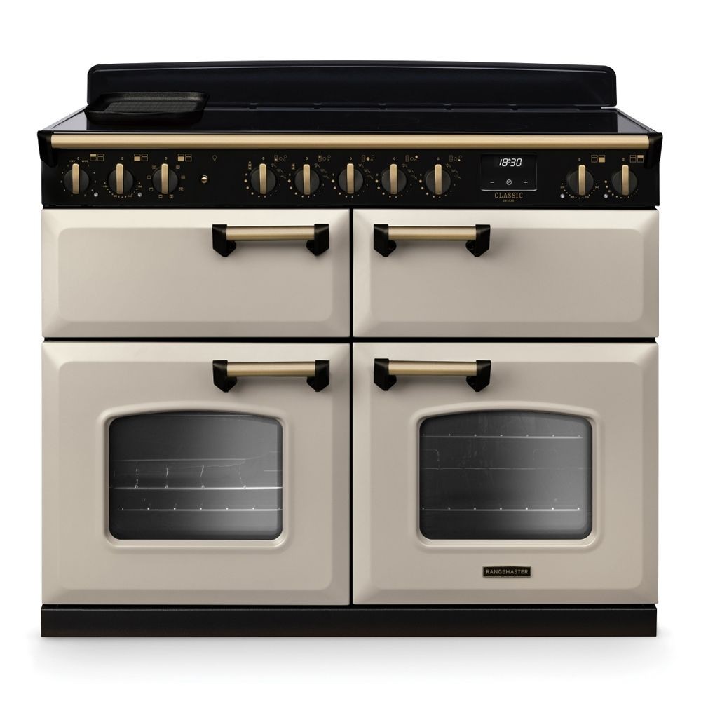 Classic Deluxe 110cm induction range cooker in pale cream with antique brass accents, featuring four oven doors, control knobs, and a sleek black top.