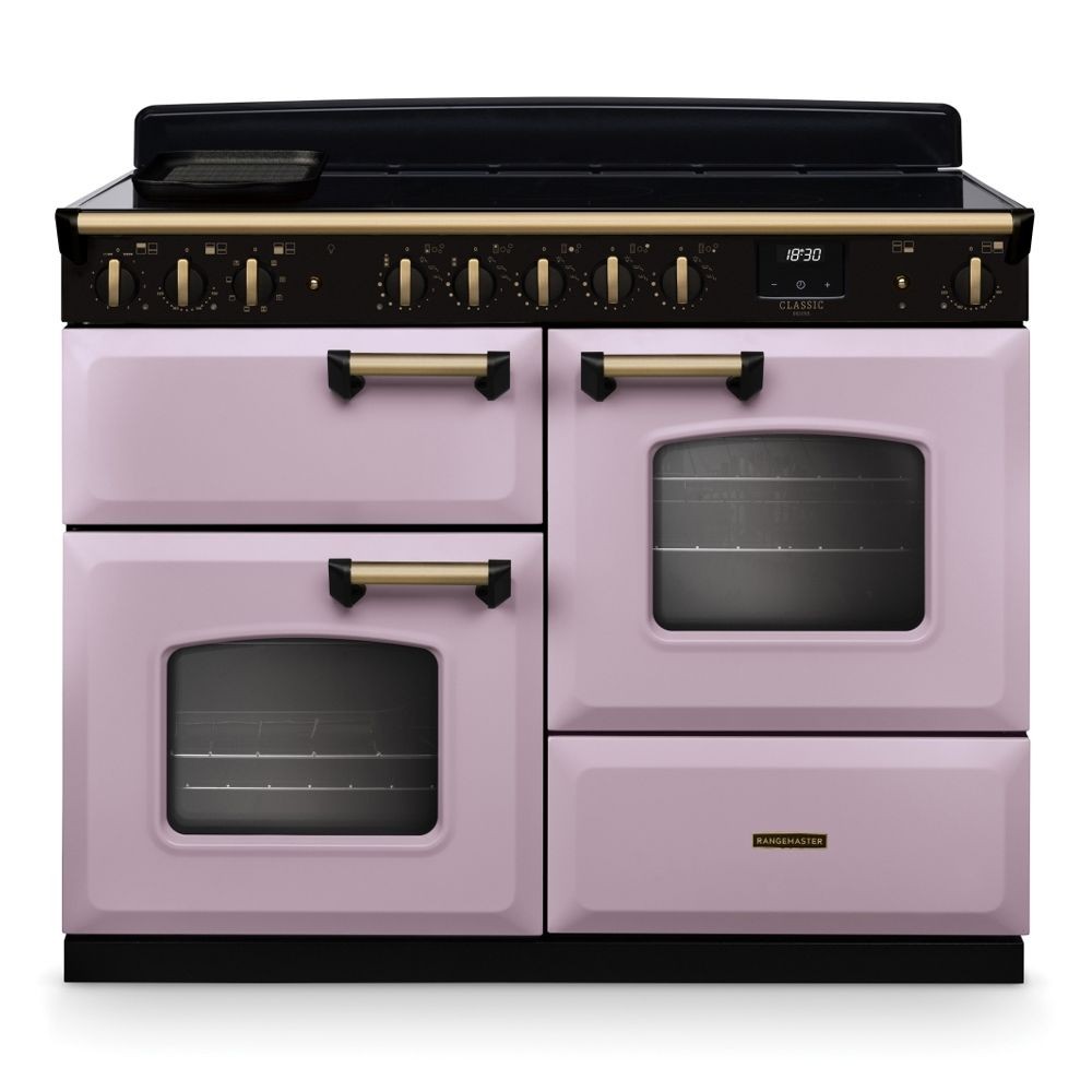 Classic 110cm induction range cooker in heather pink with antique brass accents, featuring two ovens, multiple knobs, and a sleek black induction hob.