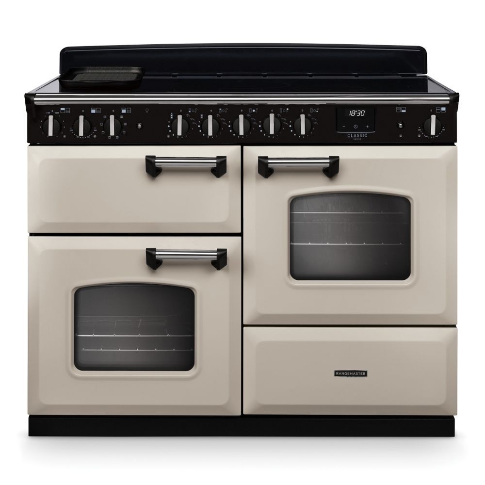 Classic Deluxe 110cm induction range cooker in pale cream with chrome accents, featuring four knobs, two ovens, and a sleek black control panel.
