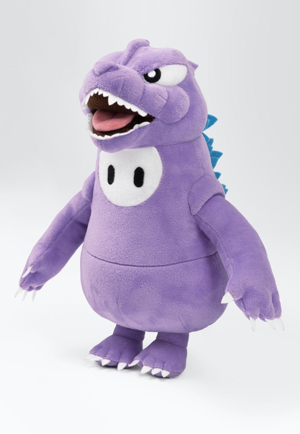 Purple plush toy resembling Godzilla with a round body, white belly, blue dorsal fins, and a wide mouth showing teeth, featuring small claws on its hands and feet.