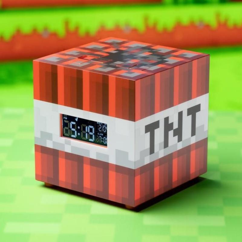 A red and white cube-shaped alarm clock designed like Minecraft TNT, featuring pixelated graphics and a digital display showing time and alarm settings.