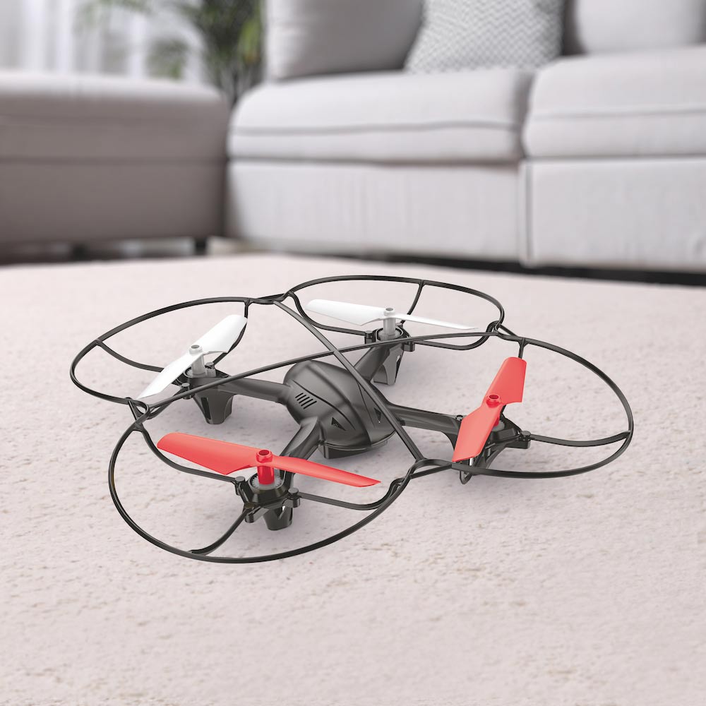 RED5 Motion Control Quadcopter Drone in red and black, featuring four propellers with red and white blades, resting on a light-colored carpet near a sofa.