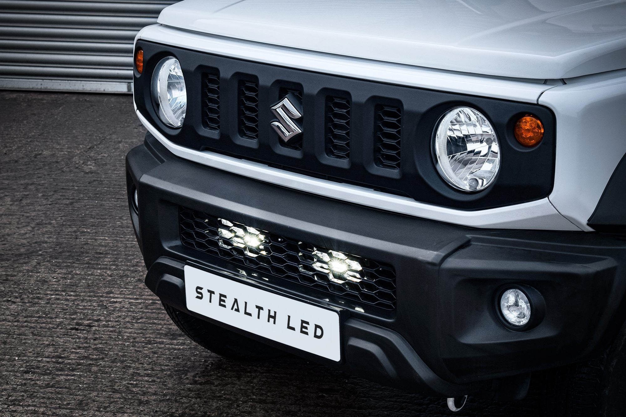 Black grille integration kit with twin 7" luminous LED lights, designed for Suzuki Jimny 2018+, featuring a sleek finish and high brightness of 10,080 lumens.