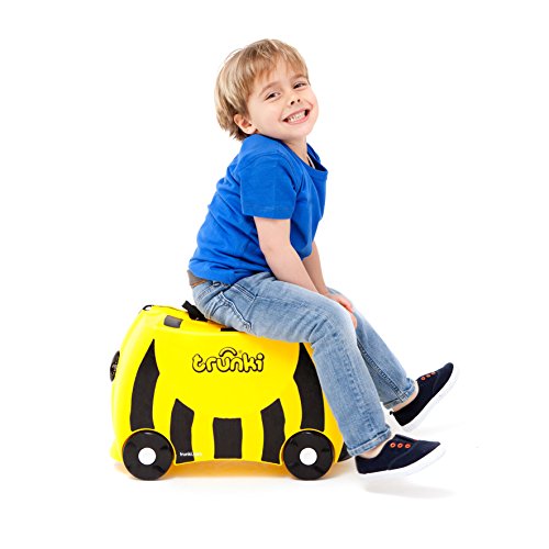 Bright yellow ride-on suitcase shaped like a bee, featuring black stripes, smiling child sitting on it, wearing a blue shirt and jeans, with wheels and a carry handle.