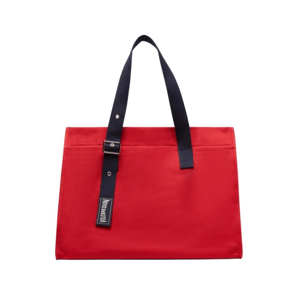 Red canvas beach bag with a navy blue strap, featuring a structured design and a branded label, ideal for summer outings.
