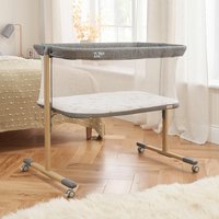 Oak rocking crib with gray mesh sides, white mattress, and wheels, designed by Tutti Bambini.