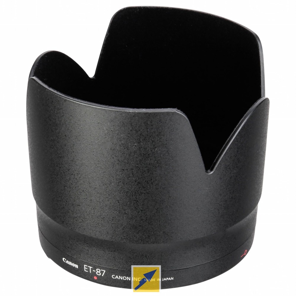 Black Canon ET-87 lens hood with a petal shape and smooth finish, featuring embossed branding and a red dot indicator for proper alignment.