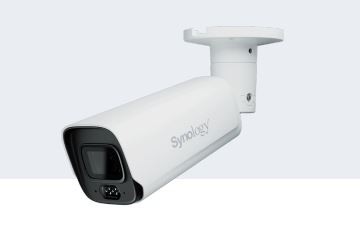 White bullet-style IP security camera with a sleek design, featuring a black lens area and Synology branding, mounted on a white bracket for indoor use.