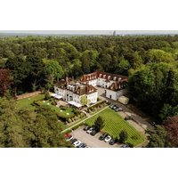 Gorse Hill Hotel surrounded by lush greenery, featuring a classic white facade and red roof, with parking area.