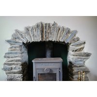 Stone fireplace with rustic wood-burning stove in Pembrokeshire seaside cottage retreat.