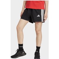Black Adidas women's shorts with white side stripes and logo, worn with black sneakers and red top.