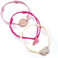 Pink and cream friendship bracelets with charms of a shoe, butterfly, and circular design by The Carat Shop.