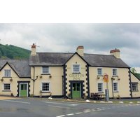 Brecon hotel stay offer at The Griffin Inn, cream building with green doors, black trim, and scenic mountain backdrop.