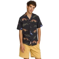Black short-sleeve Cuban shirt with colorful dinosaur print, worn by a model with yellow shorts.