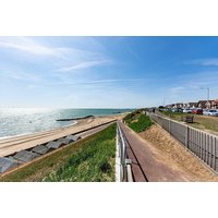 Essex seaside view with sandy beach, blue sky, and ocean waves near The Kingscliff Hotel.