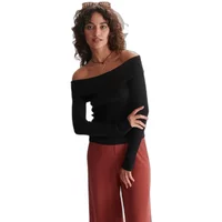 Black off-the-shoulder jumper for women, long sleeves, paired with rust-colored pants.
