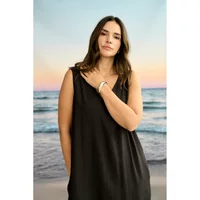 Black sleeveless dress for women by KAFFE Curve, featuring a V-neck design, worn by a model on a beach backdrop.