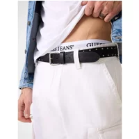 Black Guess studded belt with silver buckle, worn on white pants, visible Guess logo on waistband.