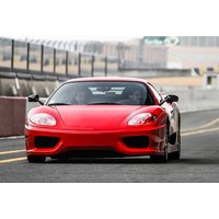 Red Ferrari 360 supercar on a racetrack, sleek design with prominent headlights and aerodynamic curves.