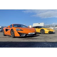Orange McLaren 570s and yellow Lamborghini Huracan parked on a track under a clear blue sky.
