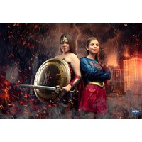 Superhero-themed photoshoot print featuring two women in costumes with a dramatic cityscape and lightning background.