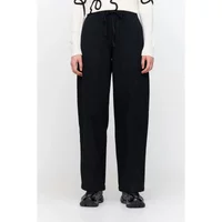 Black wide baggy fit women's jeans with drawstring waist, paired with black shoes and white top.