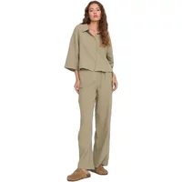 Beige wide leg trousers for women, paired with a matching loose-fit shirt, worn by a model with brown shoes.