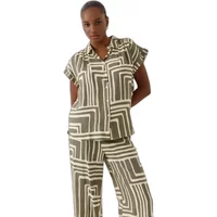 Green and white geometric patterned short-sleeve shirt with collar and button front, worn by a woman.