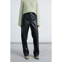 Black faux leather trousers with a straight-leg fit, paired with a light green knit sweater.