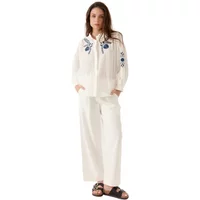 White Artlove Auralie women's blouse with blue floral embroidery on sleeves, long sleeves, and a tie-neck detail.